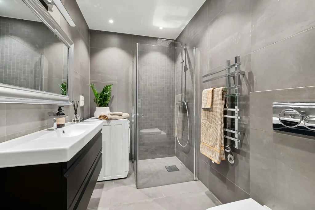 Luxury master bathroom renovation in Aurora Estates featuring a frameless glass walk-in shower with white marble wall tiles, a freestanding soaking tub, and a floating wood double vanity.