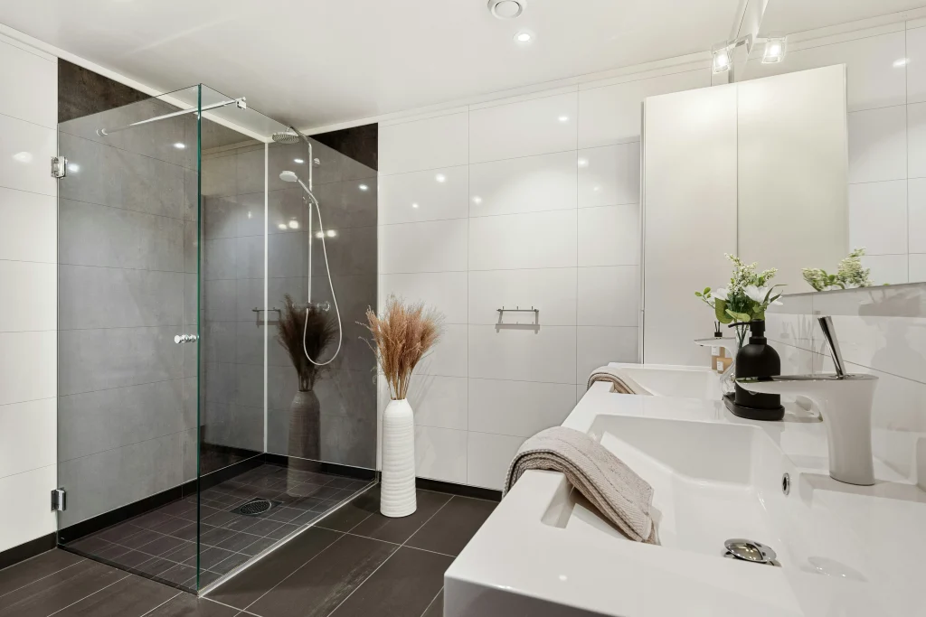 High-end luxury walk-in shower in Aurora, Ontario, featuring premium book-matched marble walls, an integrated bench, gold plumbing fixtures, and dual rainfall showerheads.