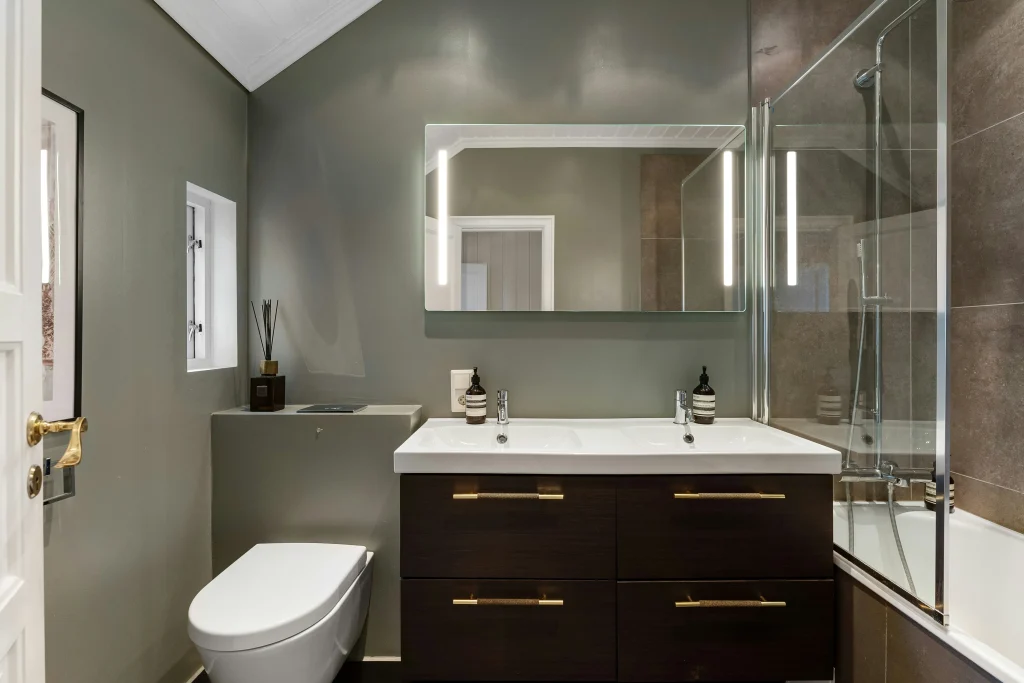 Premium bathroom renovation in Aurora Estates featuring a floating dark wood vanity, a backlit LED mirror, and a frameless glass walk-in shower with charcoal grey wall tiles.