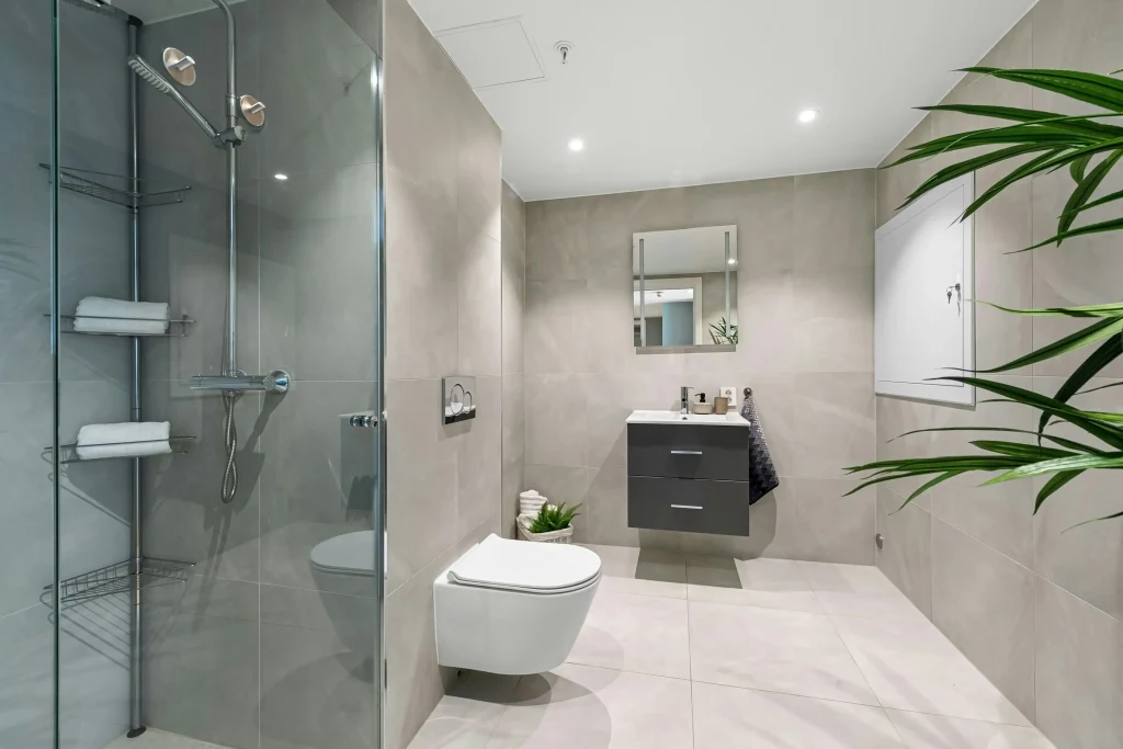 Glass shower door with dark tile and natural accents