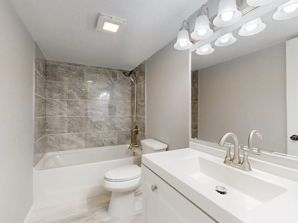 Tub-to-shower combo with marble-look tile and double vanity