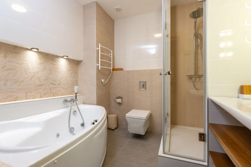 Top rated bathroom renovation in Aurora Heights, Ontario, showcasing a deep white corner bathtub with hand-carved leaf accent tiles, a floating toilet, and a glass walk-in shower enclosure.
