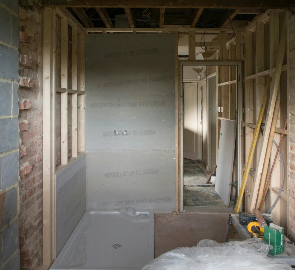 Interior view of a bathroom remodel in Aurora featuring new timber wall framing, cement backer board installation, and a walk-in shower tray.