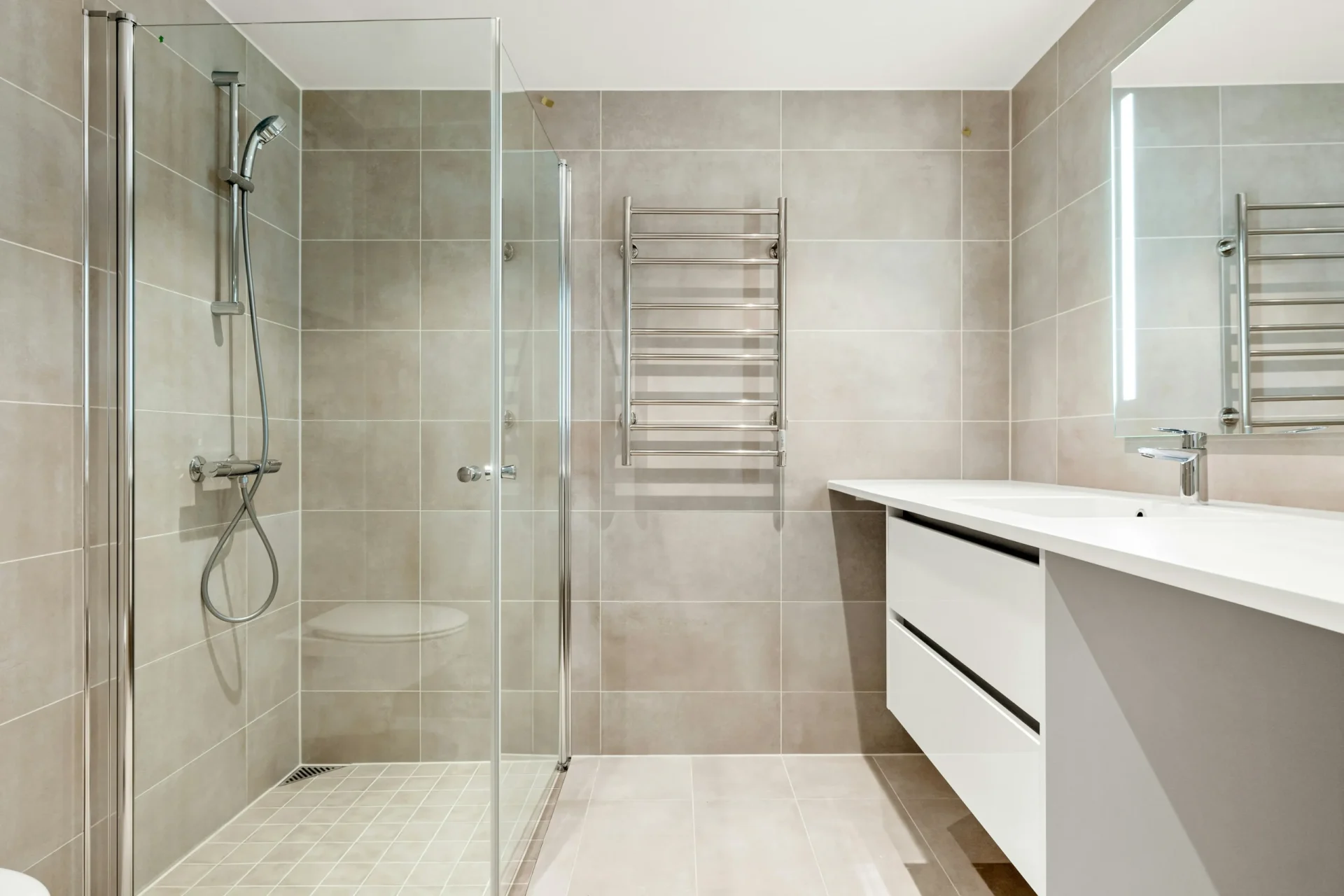 Accessible and elegant walk-in shower entry in Aurora, Ontario, featuring a slip-resistant textured tile floor, a glass screen partition, and polished silver fixtures.